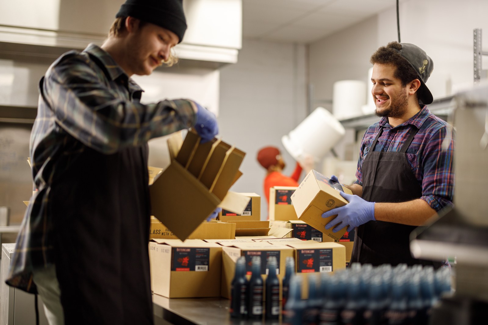 Two men packing bitters into boxes for shipping