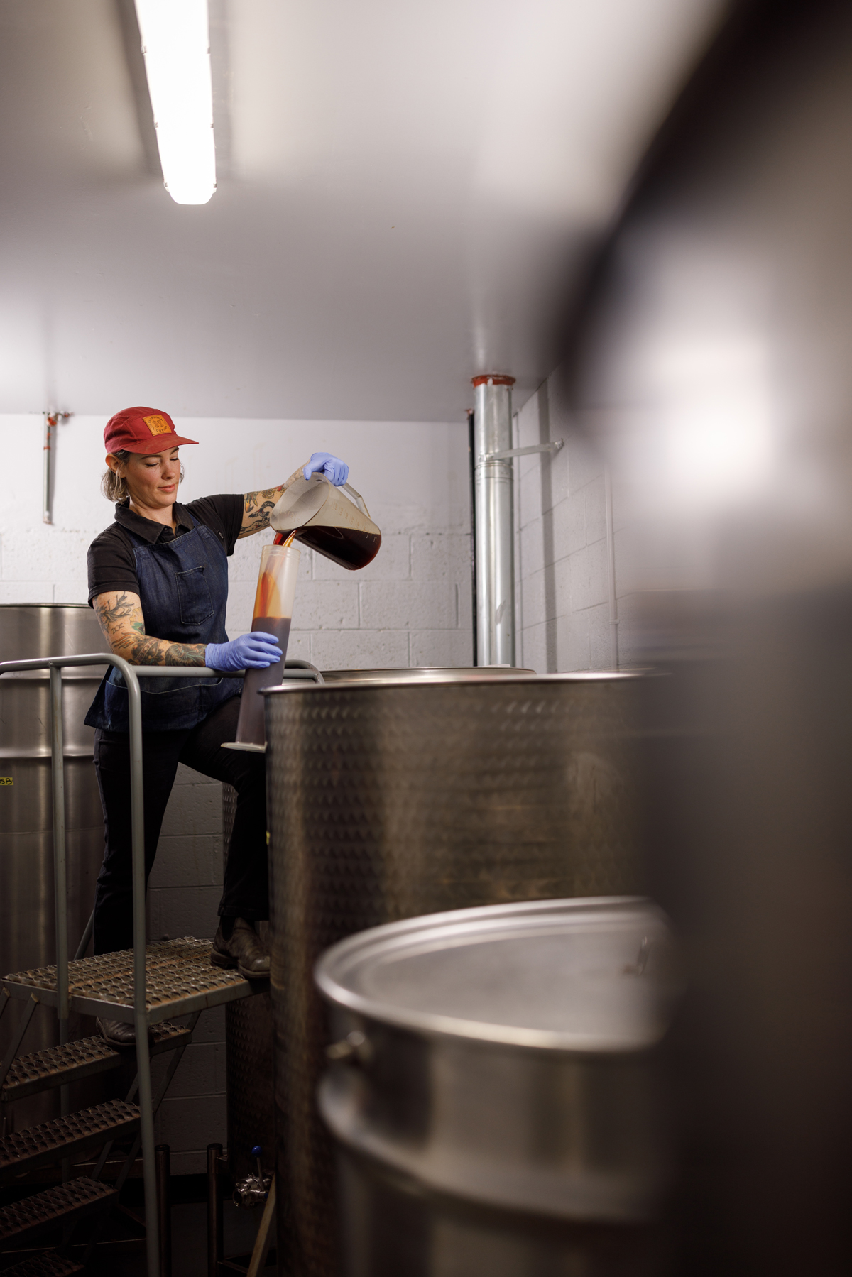 A woman pouring a large batch of bitters into a receptical